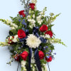 Standing floral spray with red roses, white blooms, and a navy ribbon