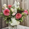 Pink and white flowers arranged in a clear glass vase