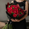 Woman holding a large bouquet of red roses wrapped in black paper
