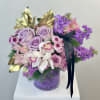 Lavender roses and purple flowers in a glass vase with gold leaves