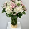 Pink and white bouquet in a clear glass vase with a gold base