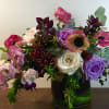 Mixed bouquet of roses, poppies, and chrysanthemums in a glass vase