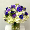 Purple and white flower arrangement in a clear glass vase