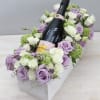 Rectangular box of lavender and white roses surrounding a rosé champagne bottle