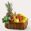 Fruit basket with pineapple, pears, apples, oranges, bananas, and a green ribbon