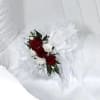 Small red and white floral corsage on white fabric