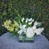 White and pale yellow flowers arranged in a rectangular glass vase