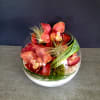 Round glass bowl with red orchids and air plants