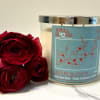 Red roses beside a cherry blossom candle in a glass jar