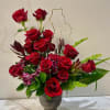 Red roses arranged in a dark vase with green foliage