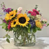 Mixed bouquet with sunflowers, hydrangeas, and pink blooms in a glass vase
