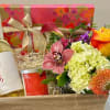 Gift basket with flowers, wine bottle, candle, and ribboned box