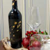 Wine bottle with a clear stemmed glass and red fruit accents