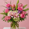 Pink roses, lilies, and orchids arranged in a clear glass vase
