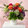 Mixed bouquet of orange and pink roses in a white vase