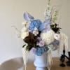 Large pastel floral arrangement in a white vase on a table