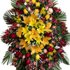 Large standing floral spray with yellow lilies, red roses, and pink blooms