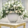 White floral arrangement in a glass vase on a gold table