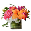 Bright mixed bouquet with orange lilies, pink roses, and white hydrangeas in a glass vase