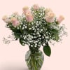 Pink roses and baby's breath arranged in a clear glass vase