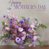 Pink and purple floral arrangement in a lavender pedestal vase
