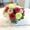 Pink and pale yellow roses arranged in a square glass vase