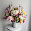 Mixed bouquet of pink, white, yellow, and purple flowers in a ribbed white vase