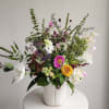 Mixed bouquet in a ribbed white vase with pink, white, yellow, and purple flowers