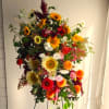 Tall mixed flower arrangement with sunflowers, red blooms, and orange flowers