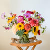 Colorful mixed bouquet in a clear glass vase on a wooden stand