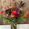 Mixed bouquet in a clear vase with orange, red, and purple blooms