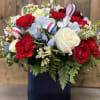 Red and white roses with blue flowers in a dark vase