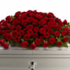 Large spray of red roses on a white casket