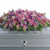 Large pink and purple floral casket spray on a gray casket