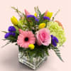 Mixed bouquet in a square glass vase with pink and yellow blooms
