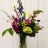 Mixed bouquet in a clear glass vase with pink, purple, and green flowers