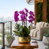Purple orchids in a gold pot on a wooden table