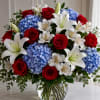 A luxurious floral arrangement featuring deep red roses, crisp white lilies, delicate