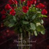 Red roses arranged in a clear glass vase with greenery