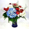 Bouquet of red roses, blue hydrangeas, and white flowers in a blue vase