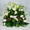 White lilies and roses arranged with green accents in a low centerpiece