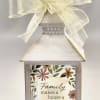 A distressed white wooden lantern topped with a sheer yellow bow this