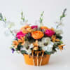 Colorful flower arrangement in an orange container with small gardening tools