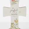 Cross-shaped decorative sign with floral print and the words "Be joyful in hope"