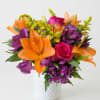 Orange lilies and purple flowers in a white vase with a pink rose