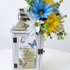 White memorial lantern with blue and yellow daisies and a remembrance message