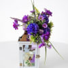 Purple floral arrangement in a white lantern with a candle inside