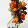 Orange and burgundy floral arrangement in a white decorative house container