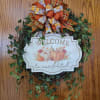 Fall wreath with a pumpkin welcome sign and plaid bow
