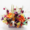 Colorful floral arrangement in a rectangular container with orange, purple, and yellow blooms